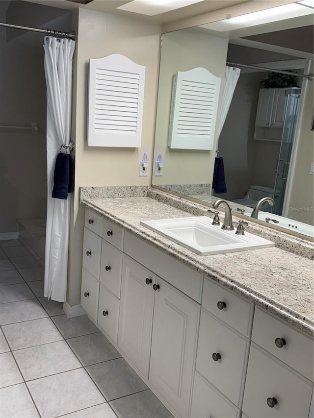 bathroom with a shower with shower curtain, tile patterned flooring, vanity, and toilet