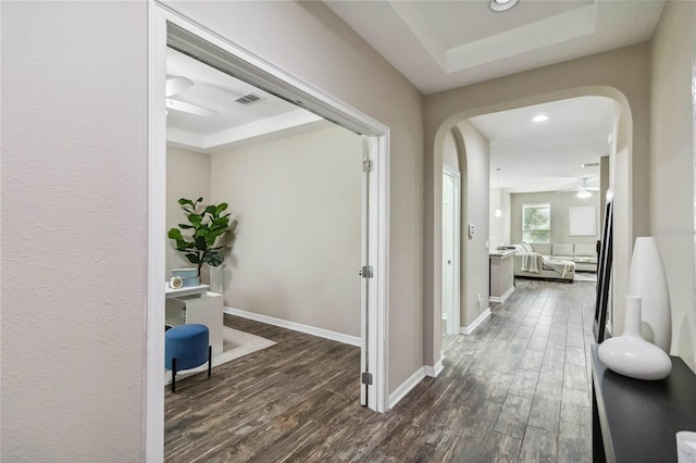 hall with a tray ceiling and dark hardwood / wood-style floors