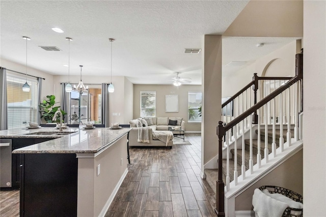 kitchen featuring light stone countertops, sink, a textured ceiling, decorative light fixtures, and dark hardwood / wood-style floors