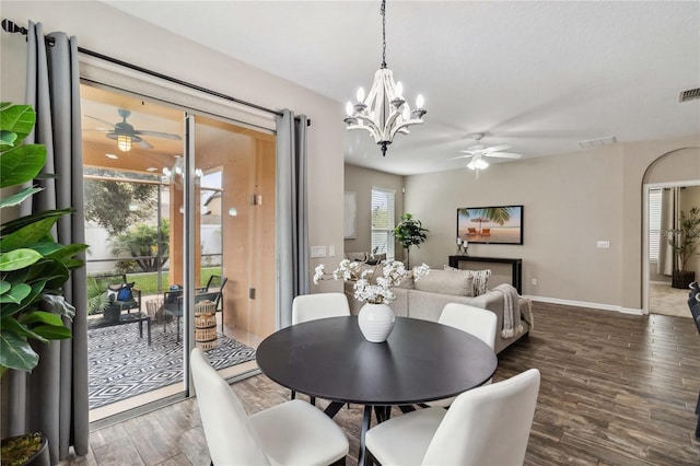 dining space with dark hardwood / wood-style flooring, ceiling fan with notable chandelier, and plenty of natural light