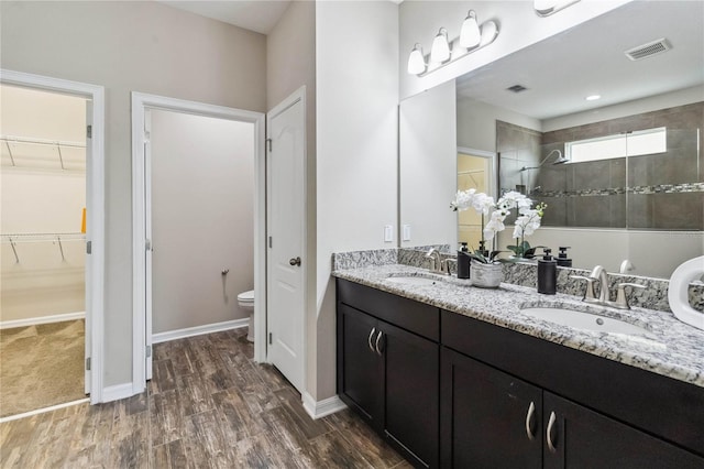 bathroom with vanity, toilet, tiled shower, and hardwood / wood-style floors