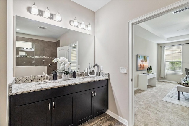 bathroom featuring vanity, a tile shower, and wood-type flooring