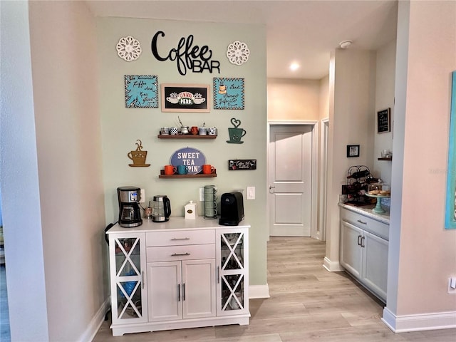 bar featuring white cabinetry and light hardwood / wood-style flooring