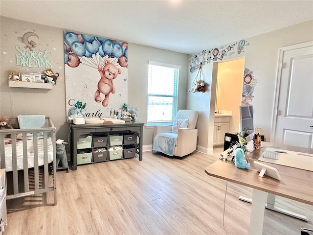 bedroom featuring light hardwood / wood-style floors, a nursery area, and ensuite bathroom