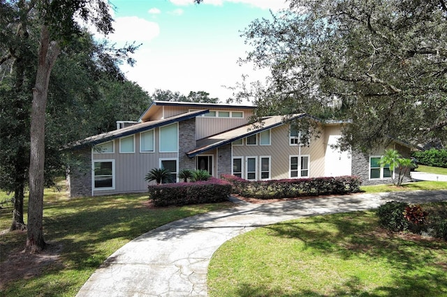 mid-century home featuring a front yard and concrete driveway