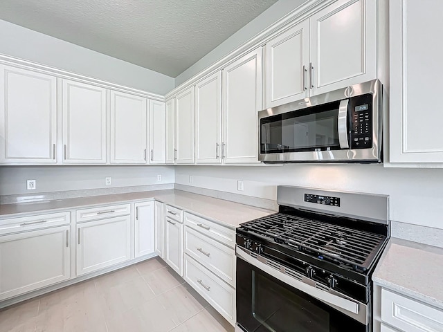 kitchen with a textured ceiling, white cabinetry, and stainless steel appliances