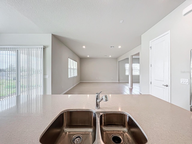 kitchen with light tile patterned floors, a textured ceiling, sink, and plenty of natural light