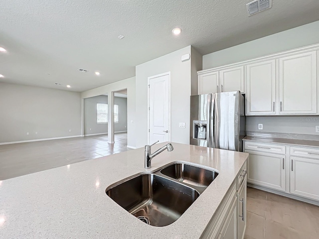 kitchen with sink, white cabinetry, stainless steel refrigerator with ice dispenser, and a textured ceiling