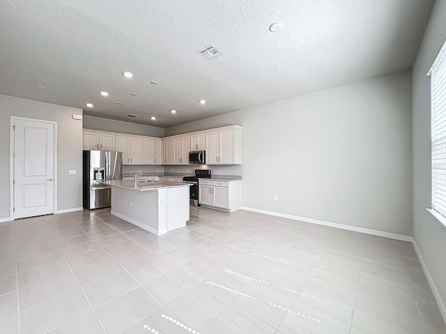 kitchen featuring sink, appliances with stainless steel finishes, a textured ceiling, and a kitchen island with sink