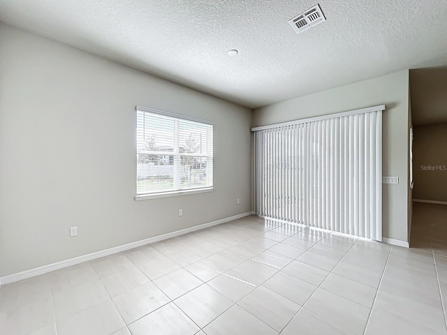 tiled empty room with a textured ceiling