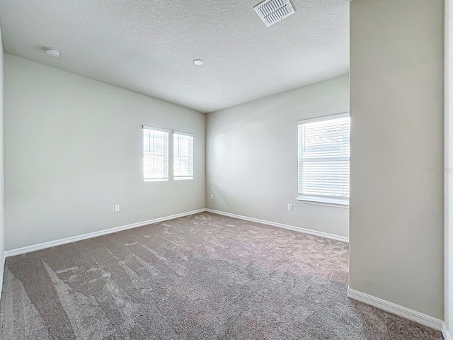 carpeted empty room with a textured ceiling