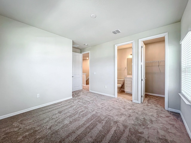 unfurnished bedroom with light carpet, multiple windows, a spacious closet, and a closet