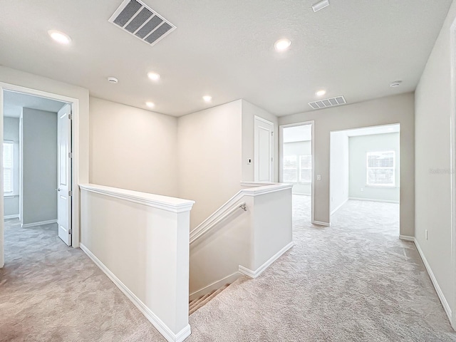 corridor featuring light colored carpet and plenty of natural light