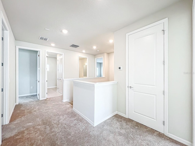 hall with light carpet and a textured ceiling