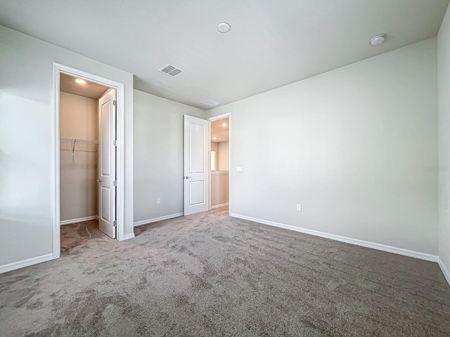 unfurnished bedroom featuring a spacious closet, a closet, and carpet floors