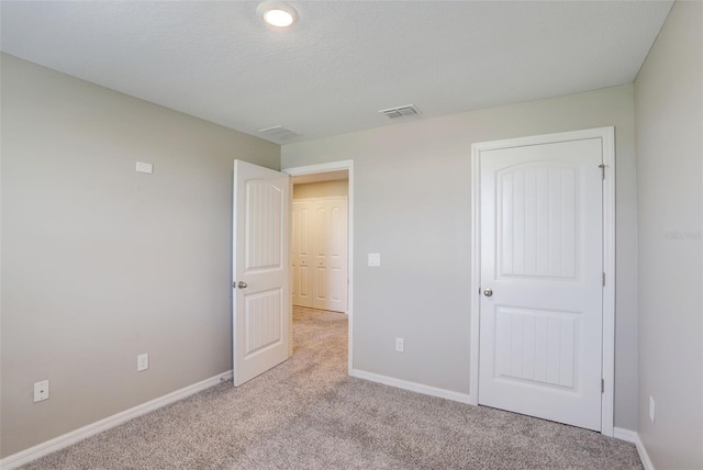 unfurnished bedroom featuring light carpet, a textured ceiling, and a closet