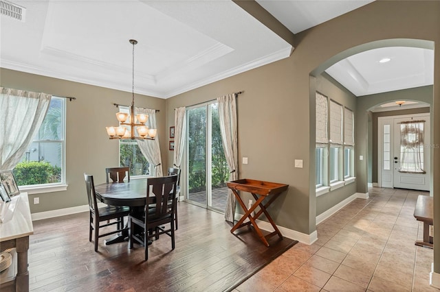 dining space featuring a healthy amount of sunlight, a tray ceiling, and light wood-type flooring