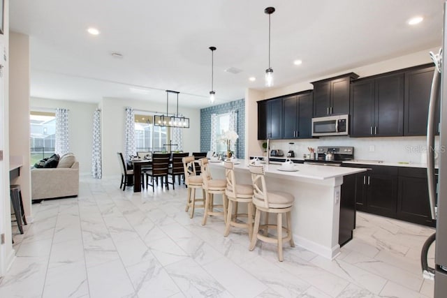 kitchen featuring appliances with stainless steel finishes, a kitchen island with sink, hanging light fixtures, and plenty of natural light