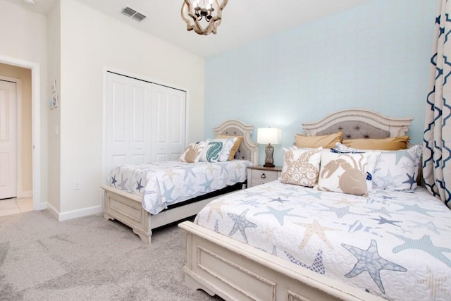 bedroom featuring an inviting chandelier, light colored carpet, and a closet