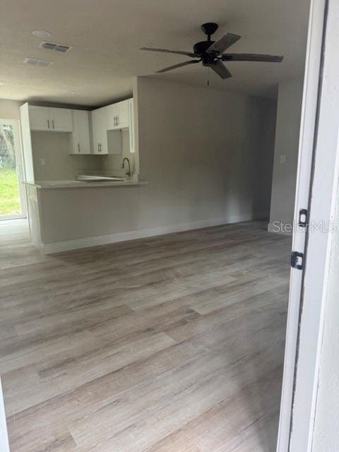 unfurnished living room with light wood-type flooring and ceiling fan