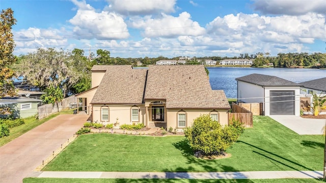 view of front of home with a garage, a front lawn, and a water view