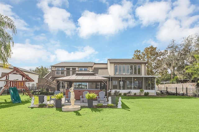 back of house featuring a gazebo, a playground, a sunroom, and a lawn