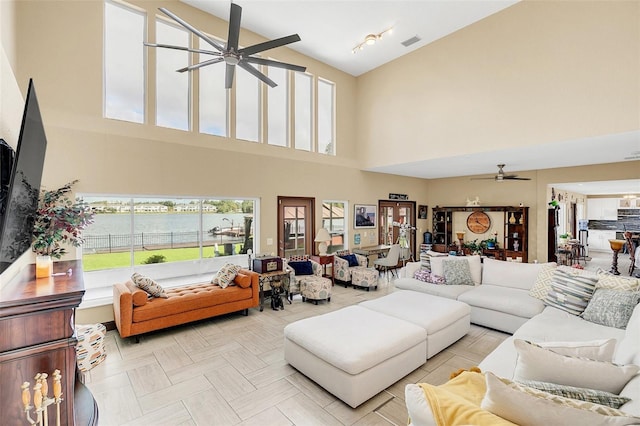 living room with a water view, ceiling fan, and a high ceiling