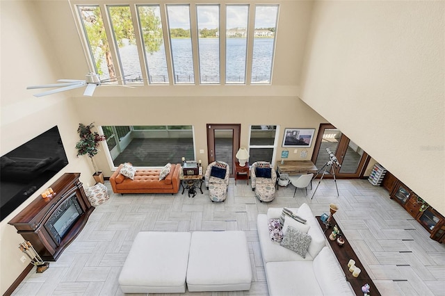 living room with a water view, light parquet flooring, a high ceiling, and ceiling fan