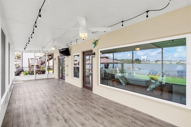 unfurnished sunroom featuring a healthy amount of sunlight, rail lighting, and ceiling fan