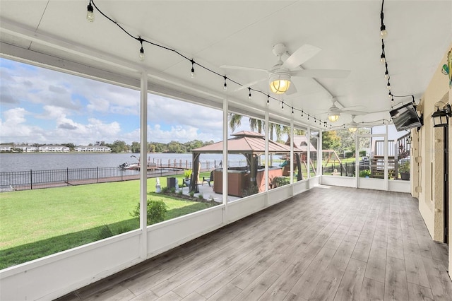 unfurnished sunroom featuring ceiling fan, a water view, and plenty of natural light