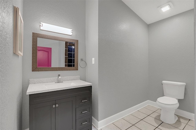 bathroom with toilet, vanity, and tile patterned floors