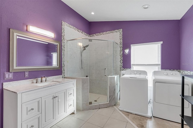 bathroom featuring a shower with door, independent washer and dryer, vaulted ceiling, vanity, and tile patterned flooring