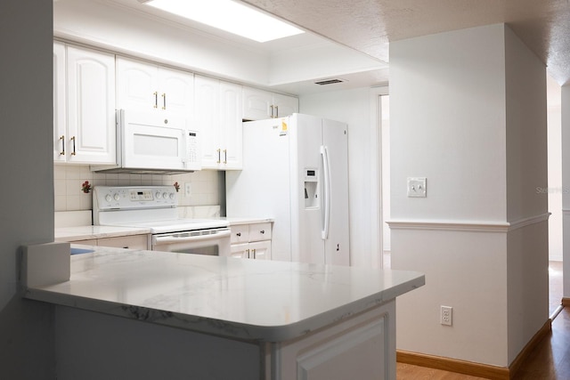 kitchen with white cabinetry, white appliances, tasteful backsplash, and kitchen peninsula