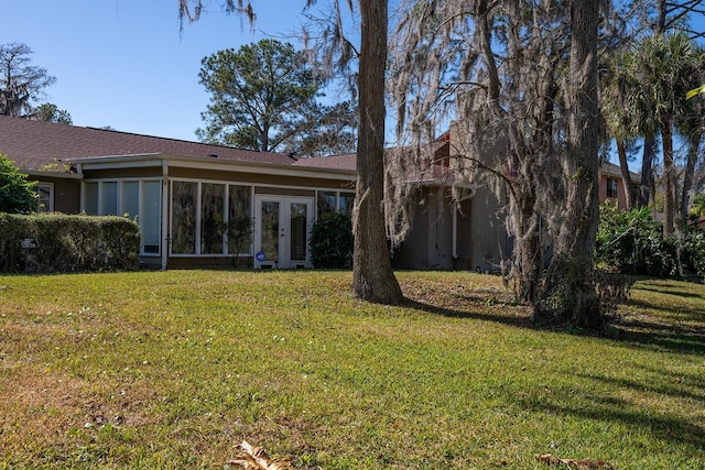 rear view of house featuring french doors and a lawn