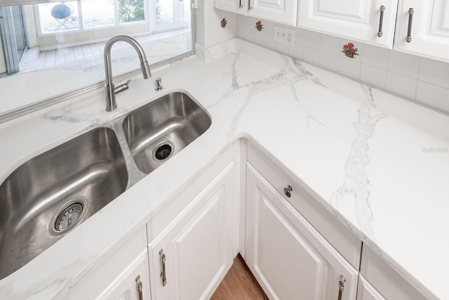 interior details with light stone counters, sink, and white cabinets