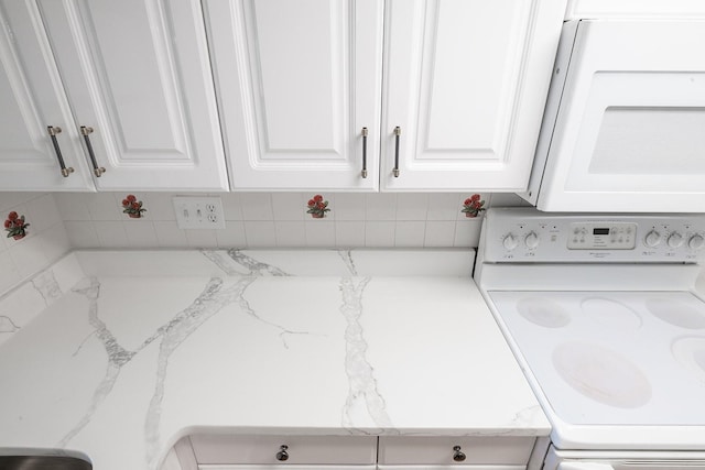 room details with washer / clothes dryer, backsplash, and white cabinets