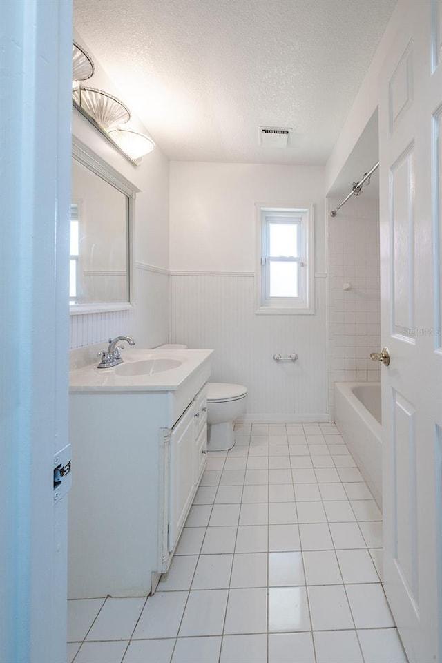 full bathroom featuring vanity, tile patterned flooring, toilet, and a textured ceiling