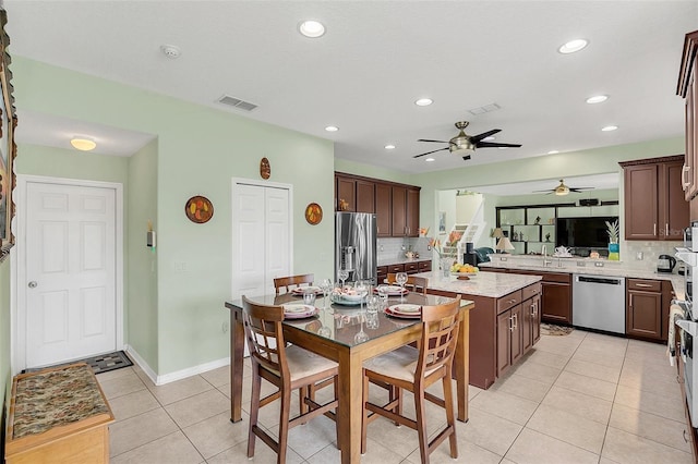 kitchen featuring backsplash, ceiling fan, stainless steel appliances, dark brown cabinetry, and light tile patterned floors