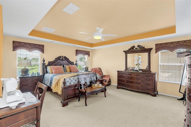 carpeted bedroom featuring a tray ceiling and ceiling fan