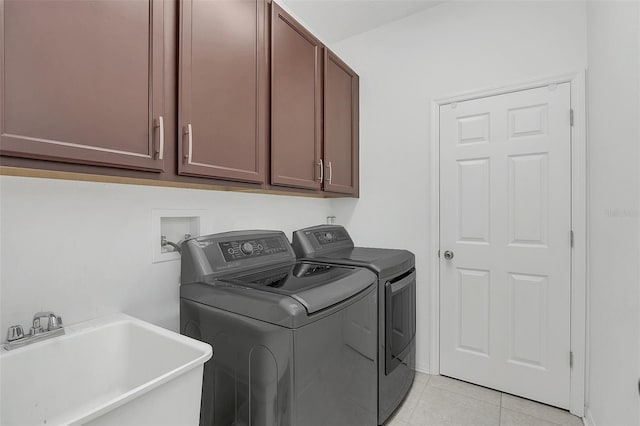 laundry area featuring sink, washing machine and clothes dryer, light tile patterned floors, and cabinets