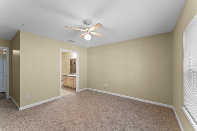 unfurnished bedroom with visible vents, baseboards, light colored carpet, multiple windows, and ensuite bathroom