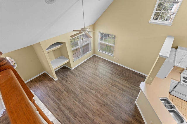 unfurnished living room featuring a healthy amount of sunlight, high vaulted ceiling, and wood finished floors