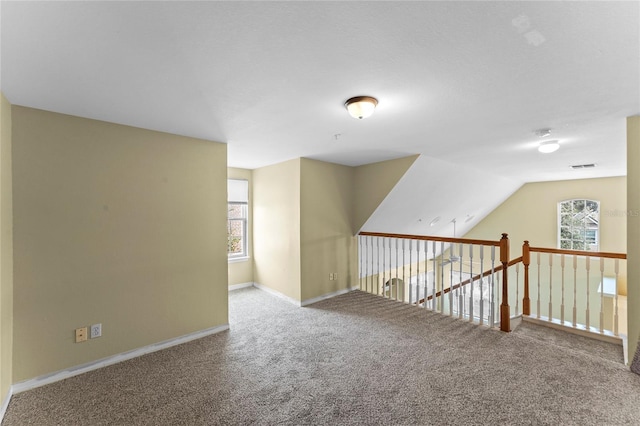 additional living space featuring visible vents, baseboards, lofted ceiling, and carpet