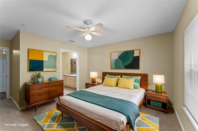 bedroom with visible vents, ensuite bathroom, baseboards, light colored carpet, and ceiling fan