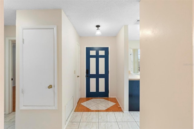 entrance foyer featuring a textured ceiling and light tile patterned floors