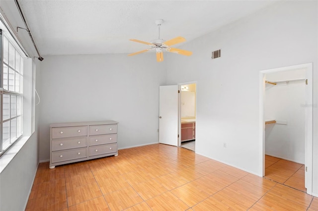 unfurnished bedroom featuring a closet, a spacious closet, high vaulted ceiling, light hardwood / wood-style floors, and ceiling fan