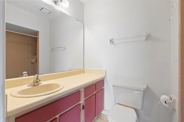 bathroom with toilet, vanity, tile patterned floors, and tiled shower