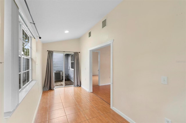 hall featuring light tile patterned floors and vaulted ceiling