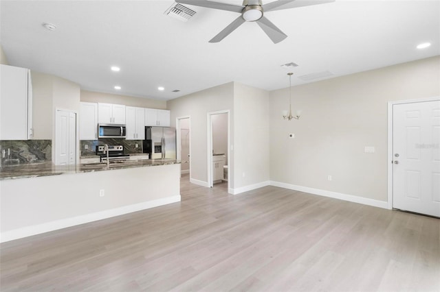 kitchen featuring dark stone counters, decorative backsplash, appliances with stainless steel finishes, decorative light fixtures, and white cabinetry