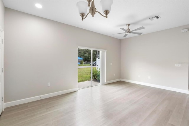 spare room with ceiling fan with notable chandelier and light wood-type flooring